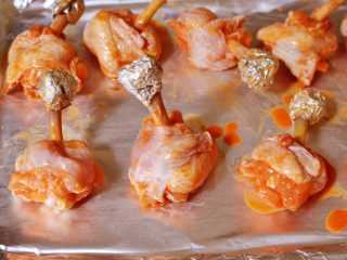 9、棒棒糖烤鸡翅根(新奥尔良口味),把骨头末端用小块锡纸包住,摆入烤盘。