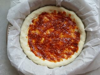 15、鸡肉海鲜披萨,15.用勺子将酱料涂满披萨底。