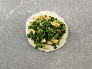 7、韭菜盒子,取一块面团，撒上少许的干粉防粘，用擀面杖擀成四边薄，中间厚的面片，再放上馅料。