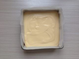 11、超柔软的棉花蛋糕,拌好的蛋糕糊倒入到铺了油纸的,18CM方型模具里。震动一下烤盘,使蛋糕糊里的大气泡震出来。