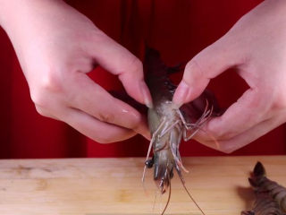 3、往虾里打入一颗蛋——虾扯蛋,接着我们开始剥虾壳，把虾头的部分剪掉，从虾的肚子处开始剥壳，也可以将虾放入冰箱里速冻，取出来带有点冰沙在虾的表面即可，这样葱虾尾一拉，就能很