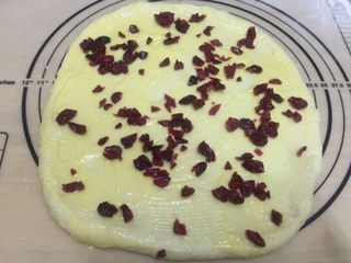 7、蔓越莓面包,将辅料里的黄油和炼乳放微波炉中20秒,搅拌均匀成炼乳黄油酱,均匀涂抹在面饼上,然后撒上蔓越莓干(炼乳黄油酱和蔓越莓干要留些后面用)