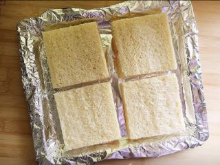 4、街头流行美食~【岩烧乳酪】,烤盘里铺锡纸,摆入四个吐司片。