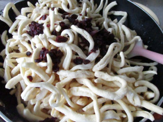 12、牛轧糖沙琪玛,放入炸好的面条和切碎的蔓越莓干，最好的倒在不沾的油布上，快速揉压成团。这个步骤要块，以面牛轧糖晾凉后不好粘合