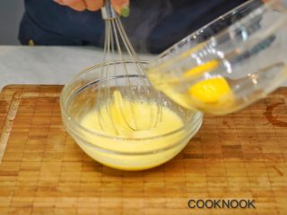 4、北海道芝士奶油杯子蛋糕,一边用蛋抽轻轻搅拌热好的牛奶与油,一边加入蛋黄, 一次加一颗蛋黄会混合的比较均匀