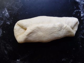 7、椰蓉花环面包,把面团自上下各三分之一处向内对折。