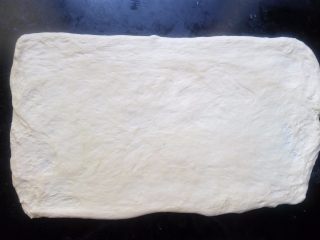 11、椰蓉花环面包,操作台撒一点点干粉，把面团擀开成长方形面片，至少需要长50cm，宽30cm，不然花环会太小，也太粗，中间圆孔小不美观。