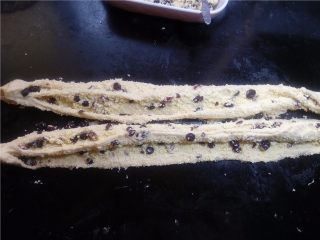 16、椰蓉花环面包,用切刀从长条正中间切开，宽度要均匀。不然编出来不美观。 切开的时候，确保一段切透，再切下一段，直到全部切开。