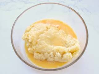 11、网红甜品+酥皮泡芙,将面团移至另外的容器中，鸡蛋打散后分三次加入面团中，每次加入蛋液后都要充分搅拌，使蛋液和面糊融合后，再加入下一次的蛋液