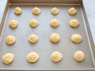 13、网红甜品+酥皮泡芙,将面糊装入裱花袋中，用圆形裱花嘴在烤盘中挤出泡芙面糊，中间要留一定的距离，以免烤制时泡芙膨胀粘在一起