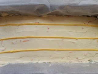 13、柠檬柚子乳酪条,单独取出的面糊加入两滴黄色色素，拌匀，装入裱花袋，在刚才抹平的奶酪糊上挤几条线