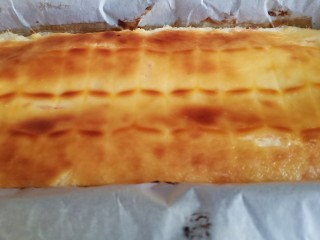 16、柠檬柚子乳酪条,出炉后取出，不要着急拖着油纸取出来，自然放凉后，放在冰箱冷藏定型，大概两三个小时。如果烤完就立即取出的话，奶酪还是半流动的，形状立马会垮掉