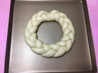 12、燕麦辫子花环汉堡面包,编好后，将两头捏合在一起，放入烤盘，进行二次发酵。（发酵时烤箱发一碗温水）