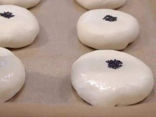 14、日式红豆包,用擀面杖沾一点水,再粘上黑芝麻,盖在红豆包上