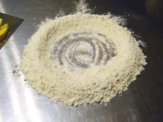 8、超详细步骤教你直接法无敌松软全麦肉松吐司,将混合好的面粉倒在操作台上，中间用手推开一个大坑。这一步骤叫做开窝