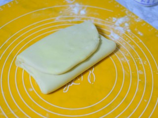 7、可颂牛角包,两边向中间叠一下,保鲜膜包好,再放冰箱冷藏15分钟,一共折叠三次,每次都要放冰箱冷藏15分钟再进行下一次折叠,第三次折叠完再冷藏15分钟