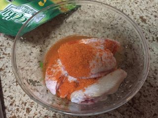 3、无油版黄金烤翅,准备一个大碗,放入鸡翅,放入Coco烤肉料,加入一小勺的盐;