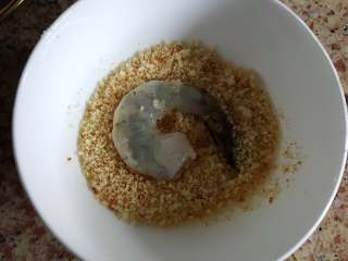 11、黄金凤尾虾,11.将虾仁放入面包糠中。