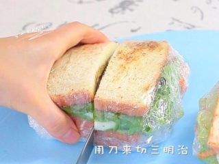 10、牛油果鸡蛋火腿三明治,准备切了。因为有了保鲜膜切的时候，中间的食物不会掉。吃的时候也很方便！