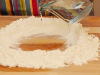 6、香酥牛肉饼,制作饼皮:中筋面粉，堆在案板中央，在中心挖一个坑，在坑中倒入温水，做一个面团