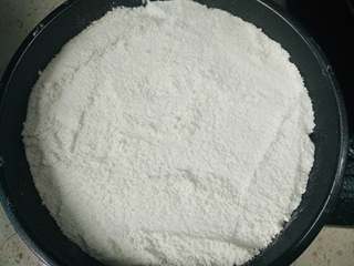 7、桂花糕,将一半粉类倒入铺了油纸的模具,用刮板刮平