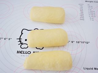 8、绵绵吐司,依次把所有的面团用擀面杖擀成牛舌状再卷起来,盖保鲜膜松弛15分钟