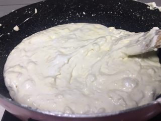 8、花生糖牛扎糖,将花生碎放入锅中关火搅拌撒上芝麻