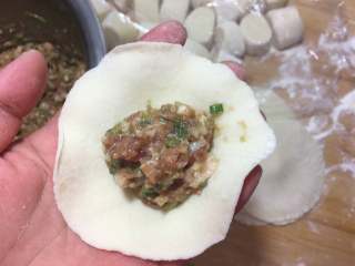 13、香葱猪肉馅小包子,取一个擀好的皮,加入适量的馅料。