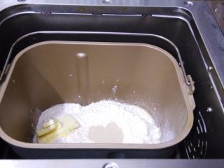1、香葱芝士面包,把主配方所有材料按照先液体再粉末的顺序放进面包桶内，黄油放一侧，选择面包机发面程序。