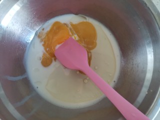 4、宝宝迷你奶香小小贝,蛋黄中加入调好的配方奶和玉米油搅拌均匀