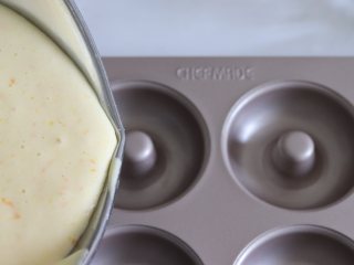 12、橙味甜甜圈蛋糕，在家就可复刻的经典美味,模具提前刷一层轻薄的黄油，蛋糕糊倒入到甜甜圈模具中。倒大约9、10分满。