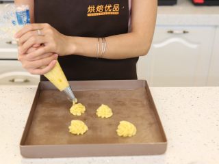 6、卡士达泡芙,6.将面糊装进裱花袋内，挤在铺了油布或者锡纸的烤盘内，也可以用勺子整形放在烤盘内。