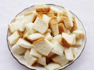 2、超好吃的蛋烤吐司块,烤箱160℃预热10分钟，土司横竖各切三刀，将土司切成小块。