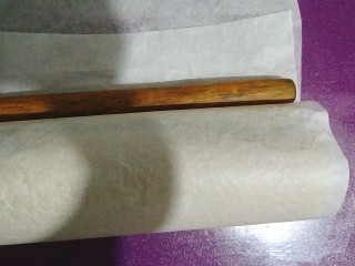 33、黑芝麻蛋糕卷,卷成卷后，借助擀面杖用力压并且往后推紧，让卷紧实；