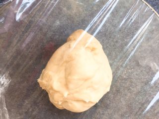 3、超级松软的    炼乳小面包,取出揉好的面团，放入无油无水的盆中。包上保鲜膜，放置温暖处，发酵至两倍大。