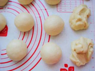 9、奶香汉堡胚,把面团放在垫子上平均分成90克一个的小剂子，排气揉成小圆球。