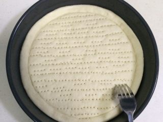 7、培根口蘑田园披萨,用叉子在饼皮上扎出排气孔，排气孔要扎透了，静置15分钟。