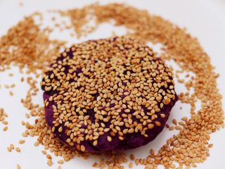 13、紫薯酸奶果仁芝麻饼,捏紧后揉圆再用手摁扁，面饼上面再蘸上白芝麻即可。