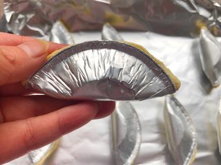 5、芒果酥,烤盘铺入锡子，把蛋挞皮对半折起来，用力捏一下，全部弄好摆到烤盘里。