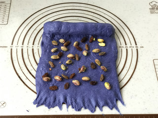 14、面包机版星空面包,先把无花果卷起，剩余的面团上摆放上葡萄干和开心果。