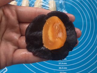 4、全面详细讲解～蛋黄酥,将17克豆沙小球压扁，咸蛋黄对半切开，放豆沙中间（你喜欢也可以加一整个蛋黄的哦）