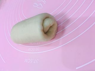 11、牛奶吐司,将醒好的面团，拿一个擀长，从上往下卷起来。