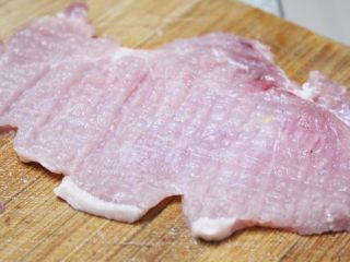 3、几乎无油的“炸”猪排,有锤肉器的话把肉锤薄一些。我用的是刀背。横竖十字敲打猪排，如图哦，纵横交错的。使得更薄更入味。