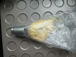 11、百香果花朵曲奇,准备一个烤盘，我用的曲奇烤盘，也可以用平烤盘，里面铺上油纸或者油布。再找一个多齿裱花嘴。把面团放进裱花袋里面。