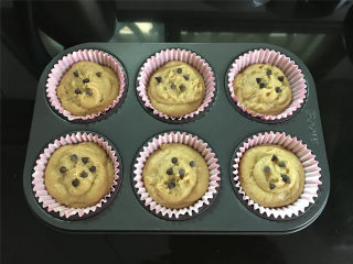 8、奶酥咖啡玛芬蛋糕,模具中放入蛋糕纸杯后把面糊放入至7、8分满再放上几粒巧克力豆作。