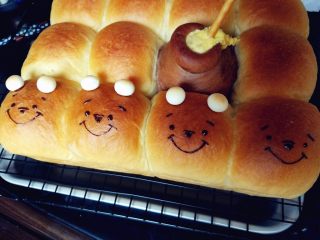 10、维尼熊跳跳虎挤挤小面包,脱模晾凉的同时,用隔水融化的黑巧克力画出维尼熊的五官,另在头部挤少许巧克力,粘住用来做耳朵的旺仔小馒头