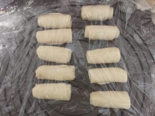 11、莲蓉蛋黄酥,再取一个卷换个方向压扁擀长卷起，用保鲜膜盖好松弛20分钟