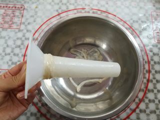 7、自制脆皮肠,在漏斗上套上肠衣，顶端留多一点