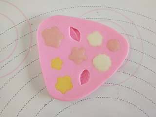 11、女巫杯子蛋糕,白巧克力隔水融化,分出一小部分加一滴色素做花心用!硅胶膜花心的部分挤一滴粉色巧克力,然后用白巧克力填满!做出帽子上的小花