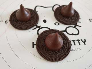 12、女巫杯子蛋糕,好时巧克力沾少许融化的巧克力,然后沾到奥利奥饼干的中间,晾凉以后做出女巫的帽子,把做好的小花沾到帽子的一边!女巫的帽子就做好了